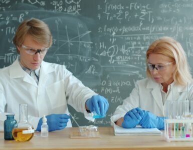 Students in lab coats conducting a classroom experiment with beakers and test tubes.