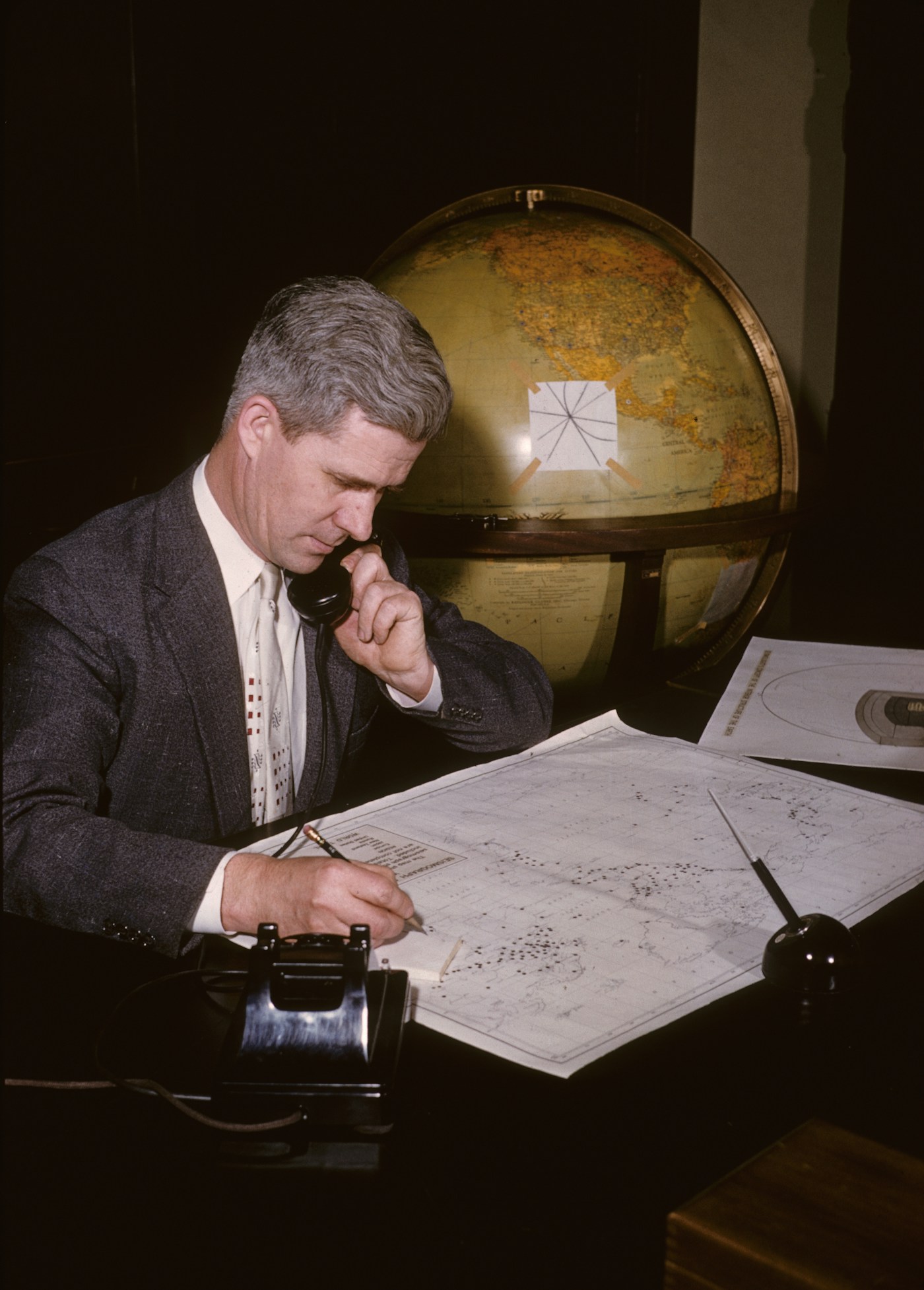 A historical seismologist reviewing written observations at a desk.