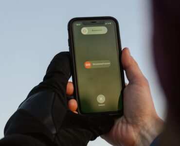 A person outdoors holding a smartphone with an emergency call option visible