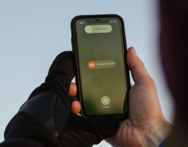 A person outdoors holding a smartphone with an emergency call option visible