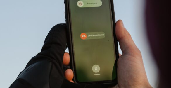 A person outdoors holding a smartphone with an emergency call option visible