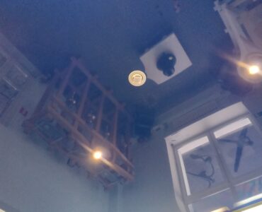 A white smoke detector mounted on a ceiling where rising smoke can reach it.