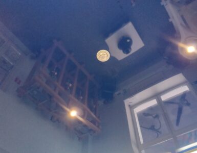 A white smoke detector mounted on a ceiling where rising smoke can reach it.