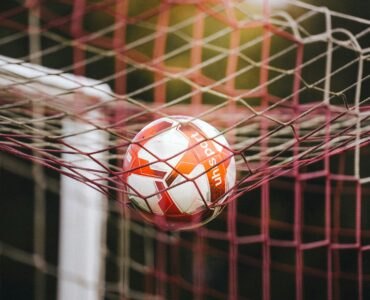 A soccer ball caught in the goal net after a shot.