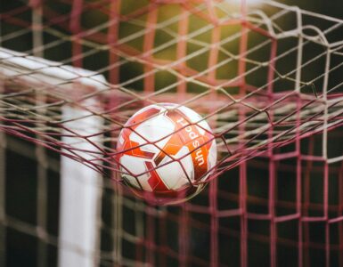 A soccer ball caught in the goal net after a shot.