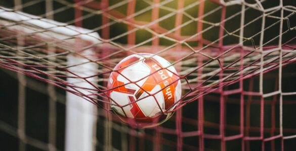 A soccer ball in the goal net after a close scoring play