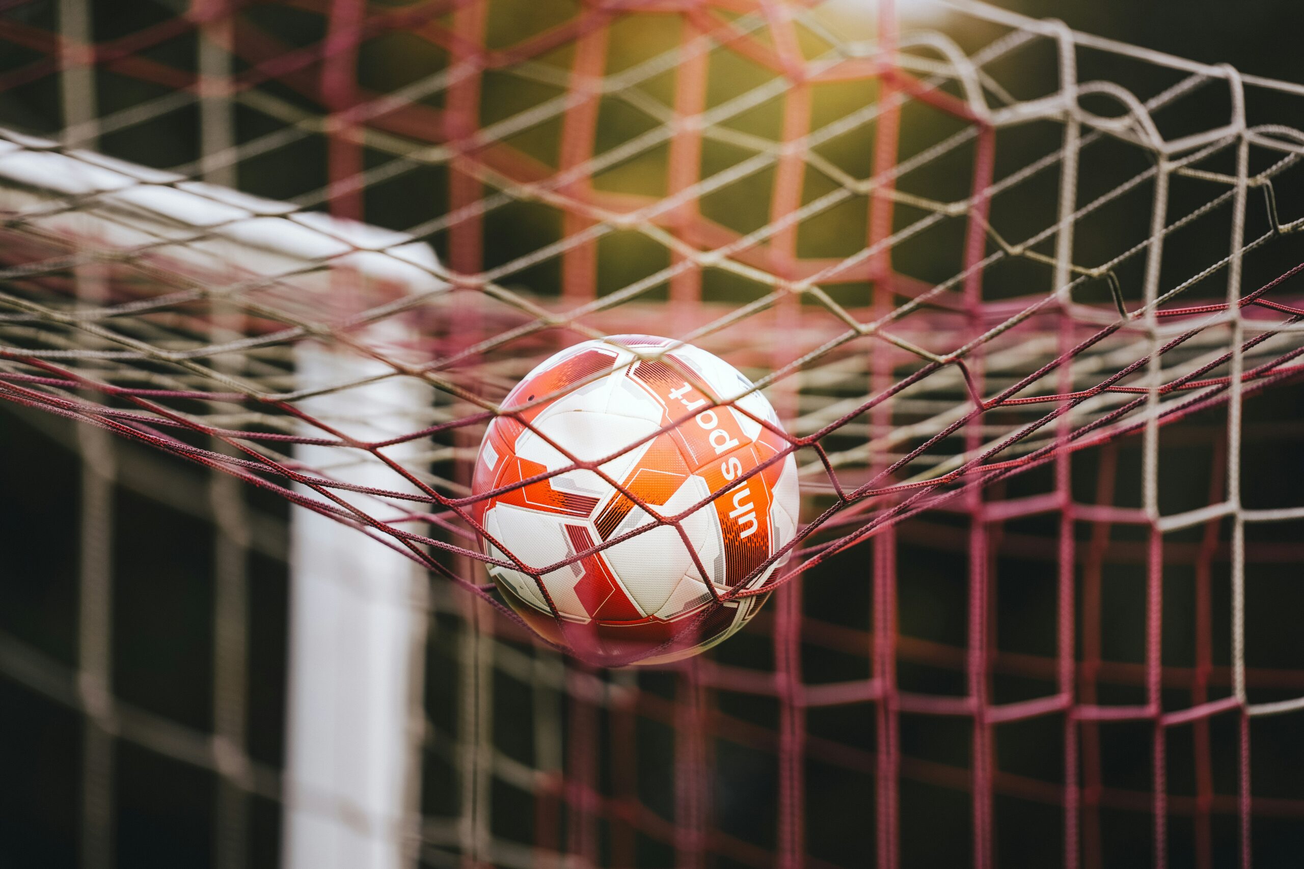 A soccer ball in the goal net after a close scoring play
