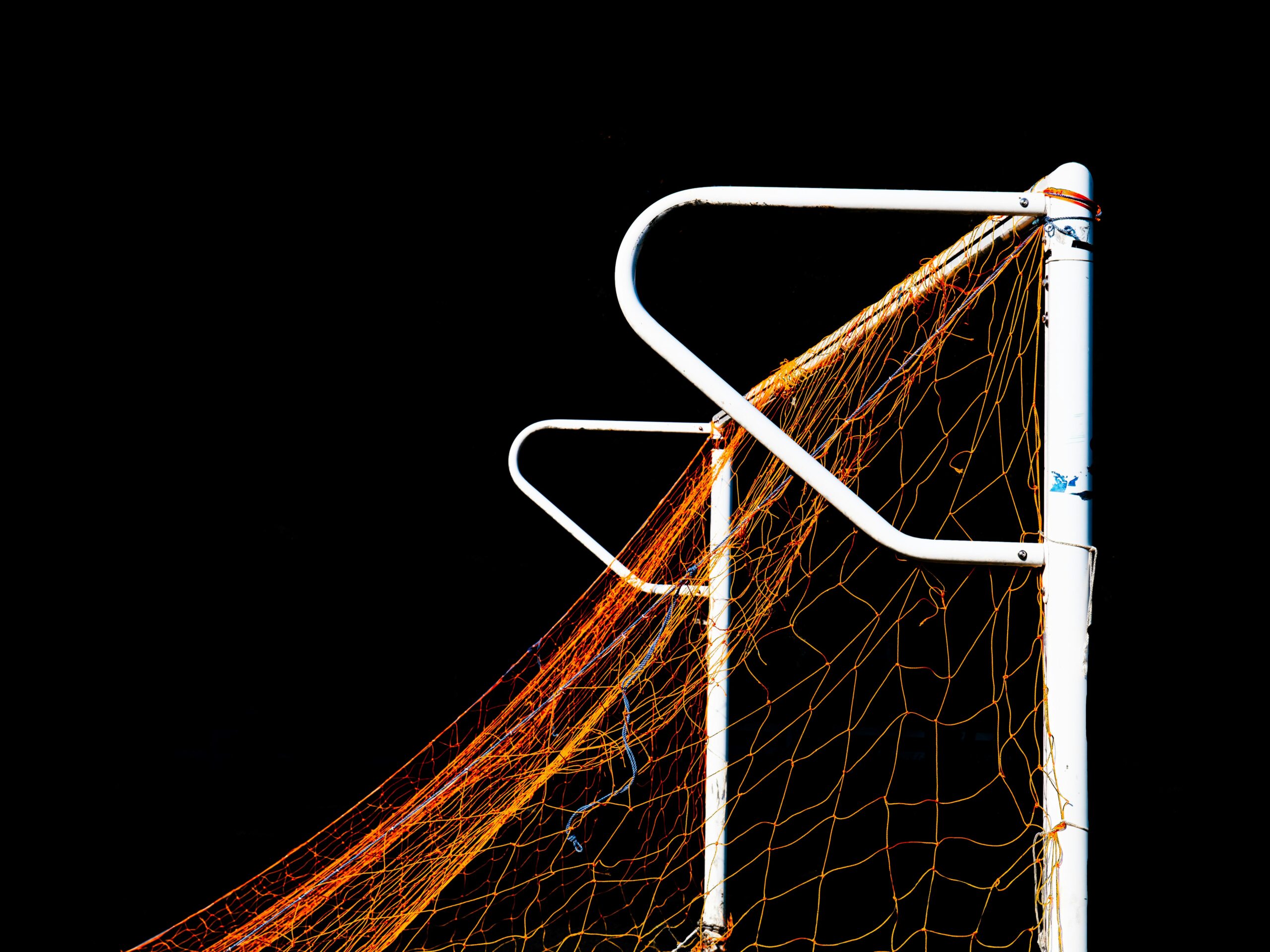 A soccer goal net and frame against a dark background.