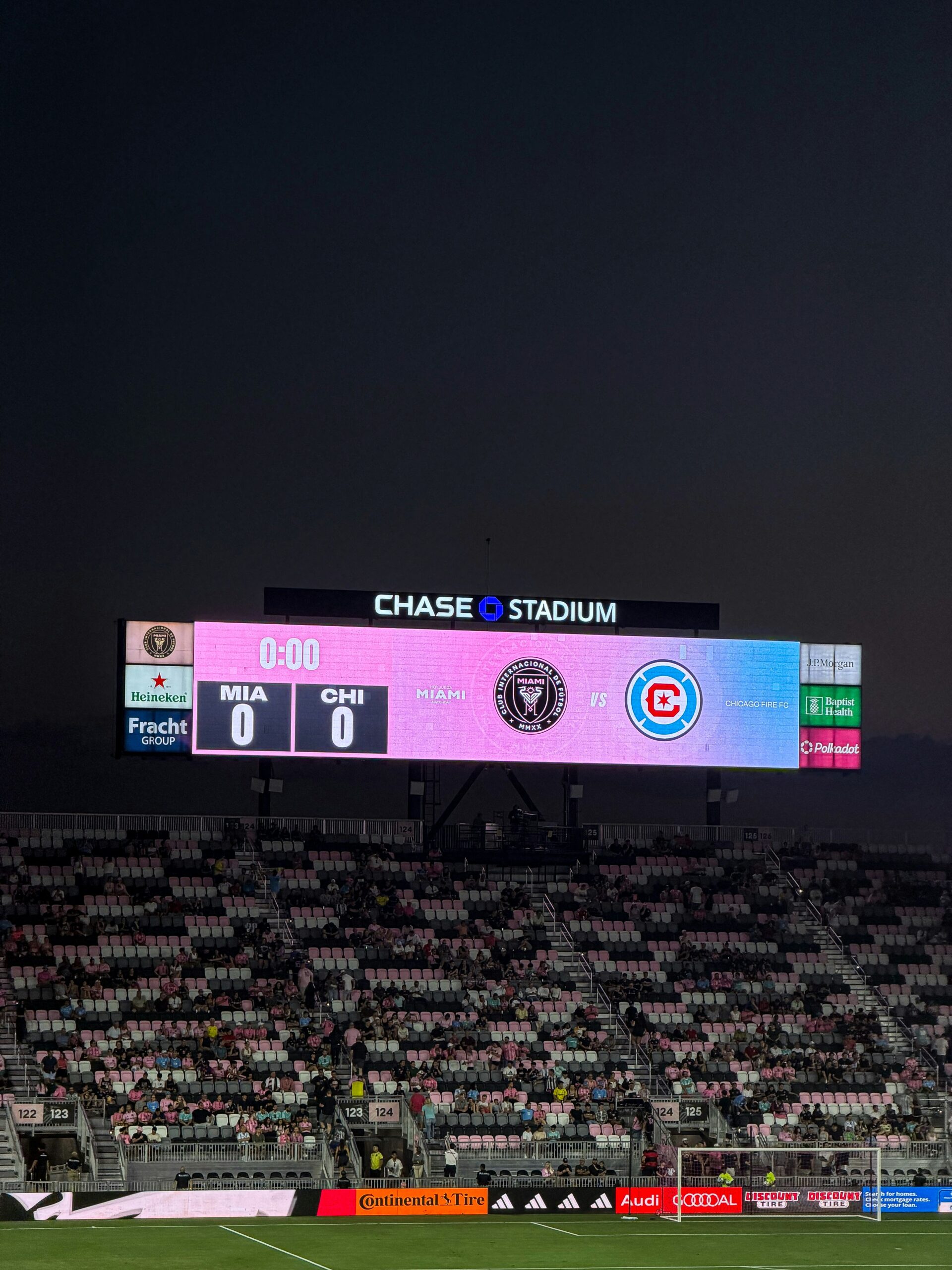 A stadium scoreboard showing a soccer match score at night.