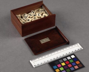 A historic spelling alphabet box filled with letter tiles.