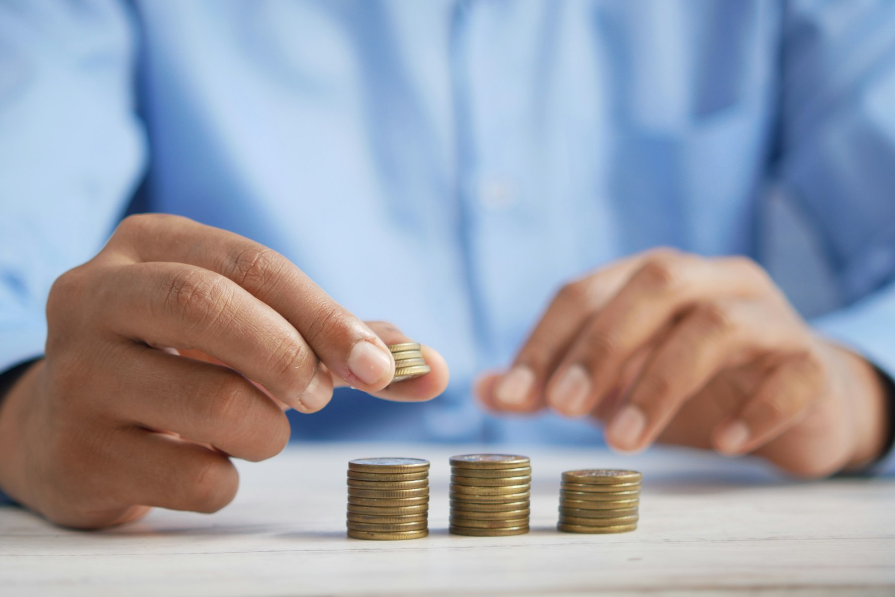 Hands stacking coins to show how interest rates change borrowing costs.