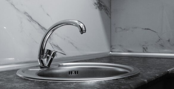 A clean stainless steel kitchen sink and faucet with a reflective metal surface