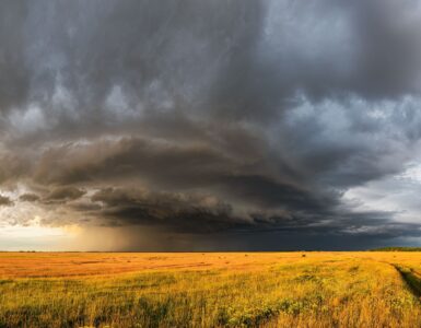 Dark storm clouds spreading across a rural field before severe weather.