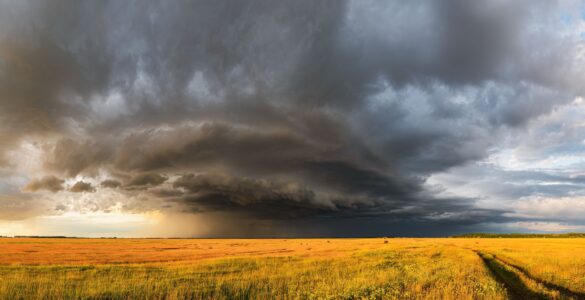 Dark storm clouds spreading across a rural field before severe weather.