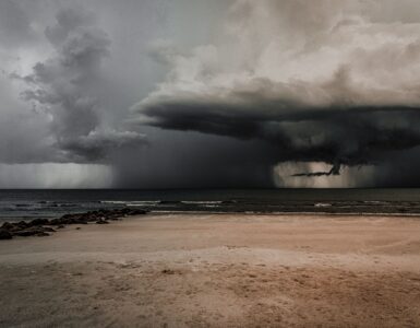 Dark storm clouds gathering over a beach and ocean before severe weather.