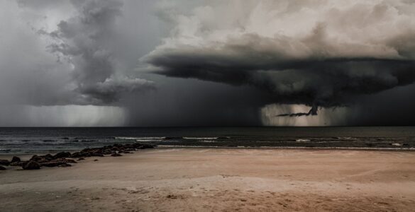 Dark storm clouds gathering over a beach and ocean before severe weather.