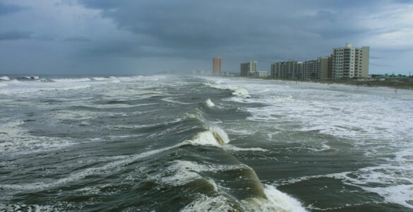 Storm-driven waves approaching a coastal city under dark clouds
