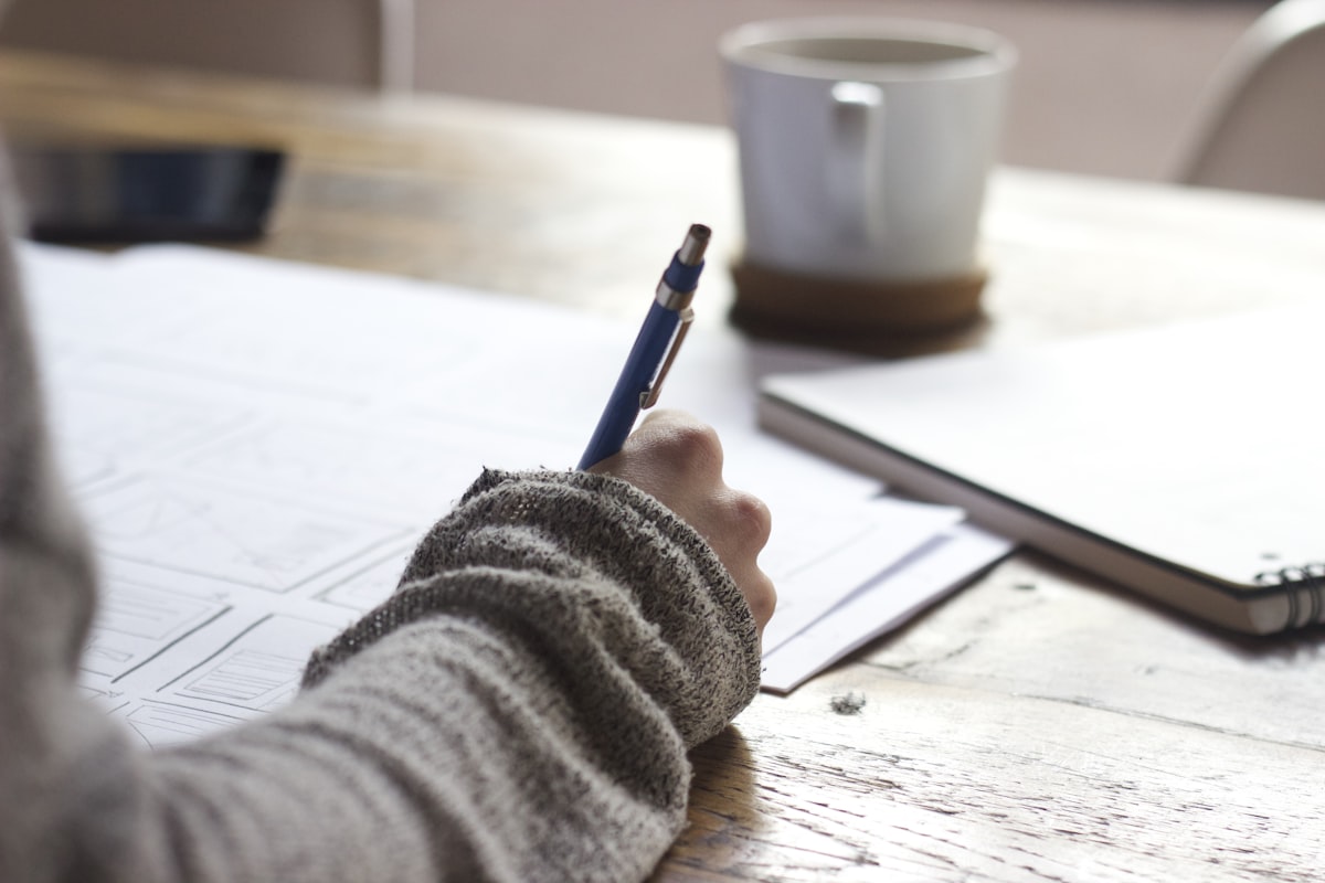 A student writing notes while planning scholarship applications