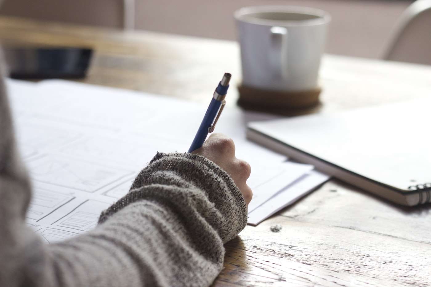 A student writing notes while studying at a desk