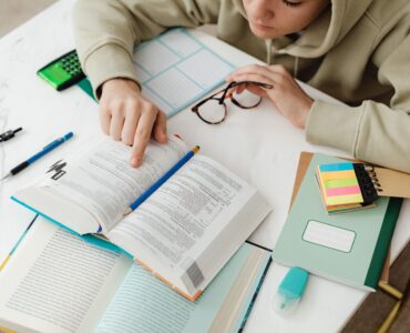 A student studies algebra with textbooks, notes, and a calculator at a desk