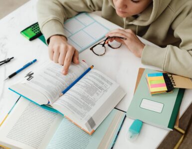 A student studies algebra with textbooks, notes, and a calculator at a desk