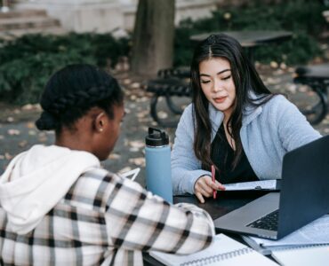 Two students review papers and a laptop while planning college coursework.