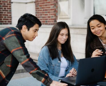 Students reviewing college options together on a laptop