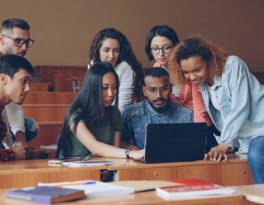 Students gathered around a laptop reviewing academic information