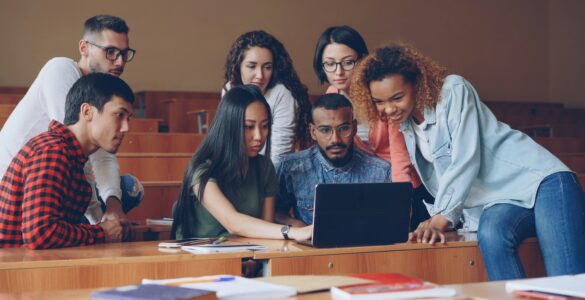 Students gathered around a laptop reviewing academic information