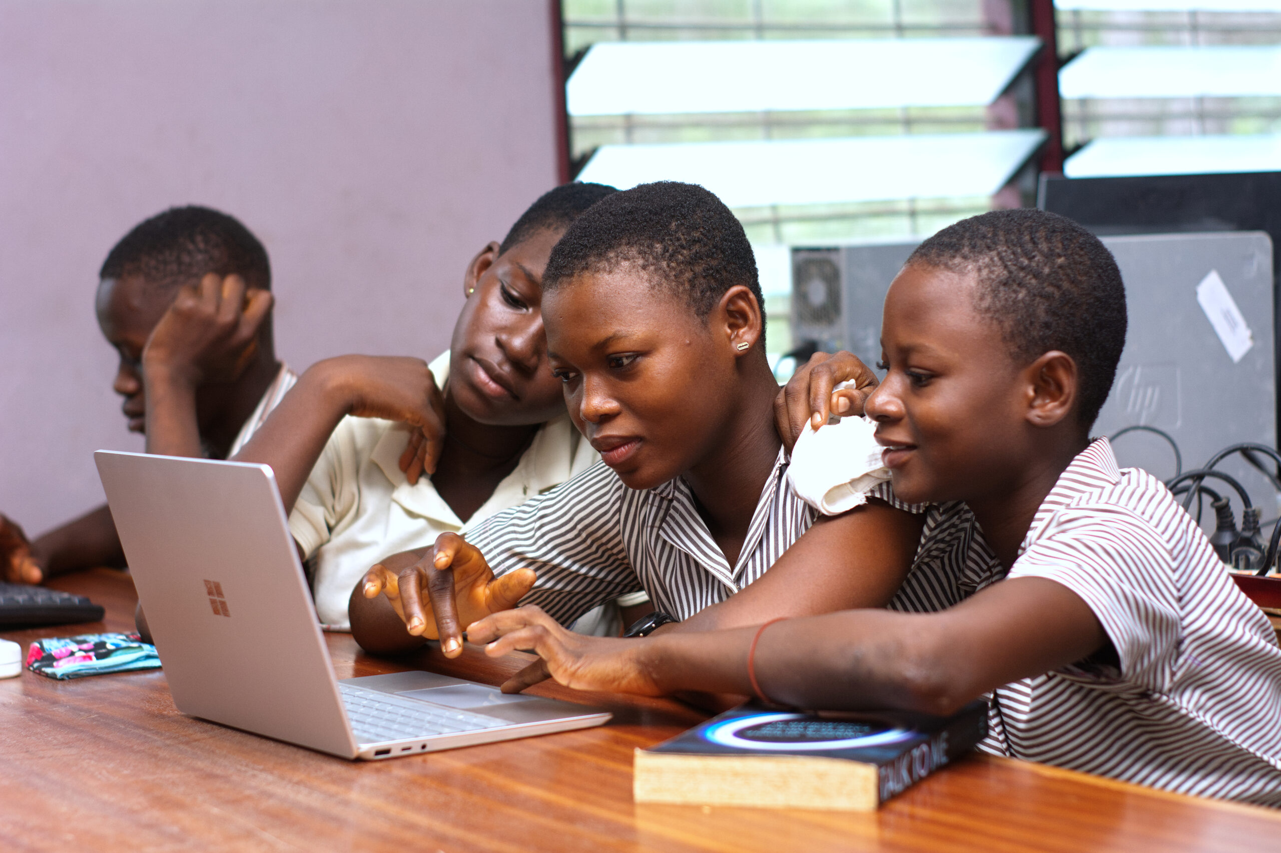 Students work together around a laptop while reviewing a digital course space.