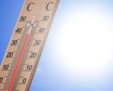 A thermometer in bright summer sunlight showing hot outdoor conditions.
