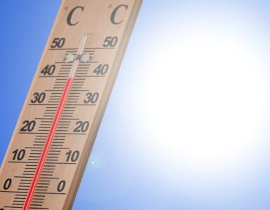 A thermometer in bright summer sunlight showing hot outdoor conditions.