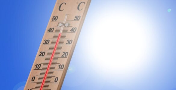 A thermometer in bright summer sunlight showing hot outdoor conditions.