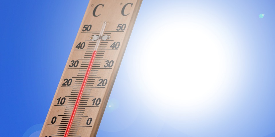 A thermometer in bright summer sunlight showing hot outdoor conditions.