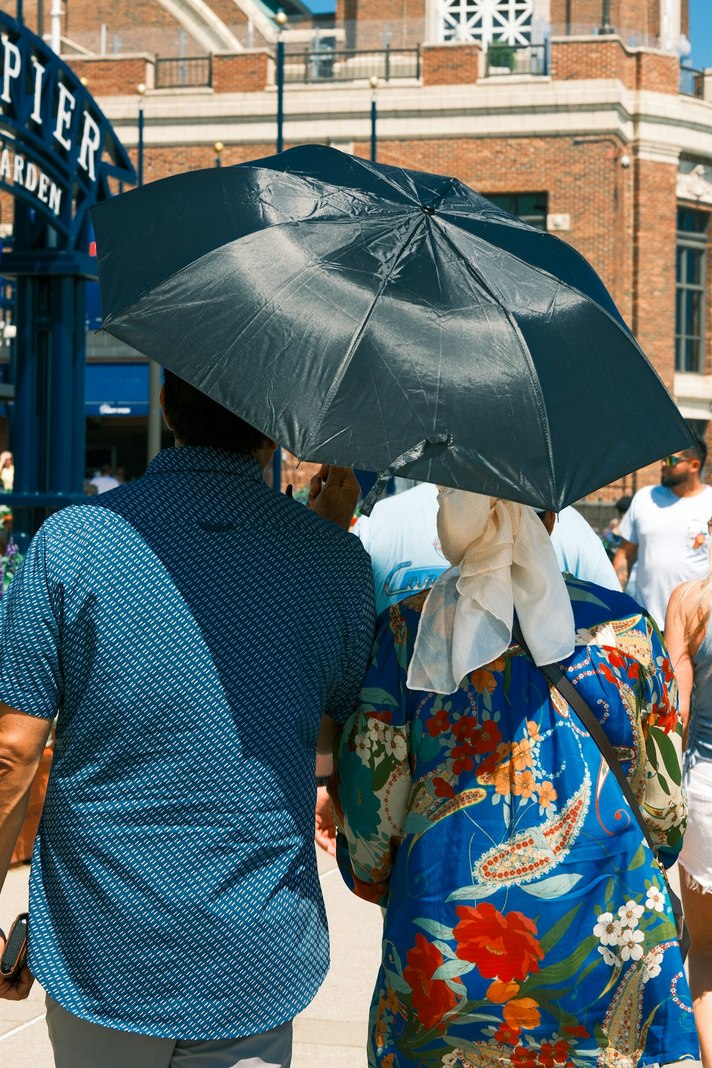 People walking with an umbrella for shade on a sunny day