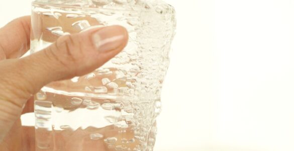 Tap water filling a clear drinking glass from a kitchen faucet.