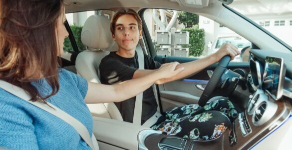 A teen driver practices with a parent sitting beside him in the passenger seat
