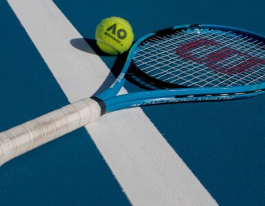 A tennis racket and ball on a blue hard court