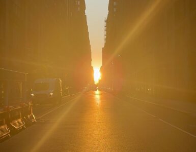Sunlight shining down a dense city street between tall buildings