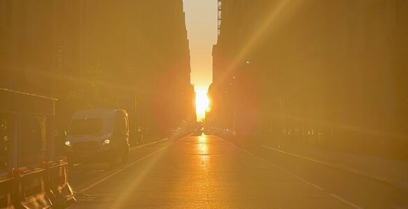 Sunlight shining down a dense city street between tall buildings