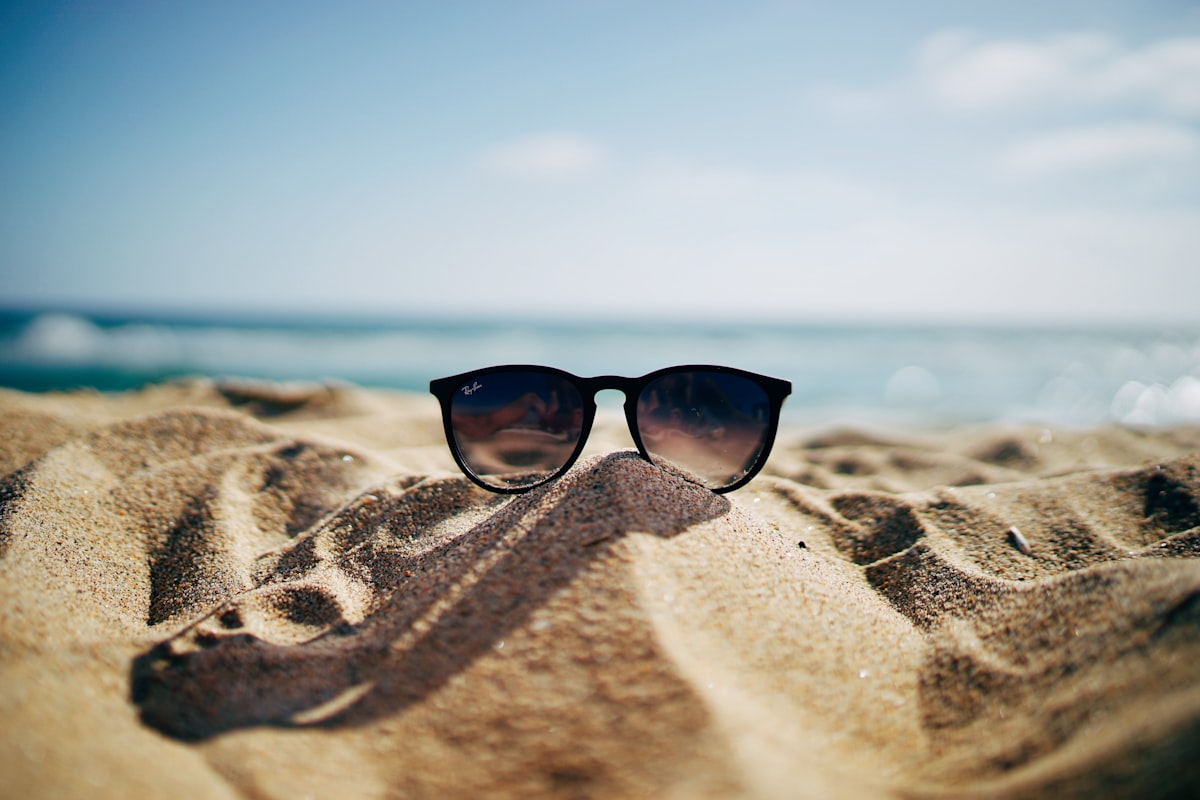 Sunglasses resting on sand in bright sunlight