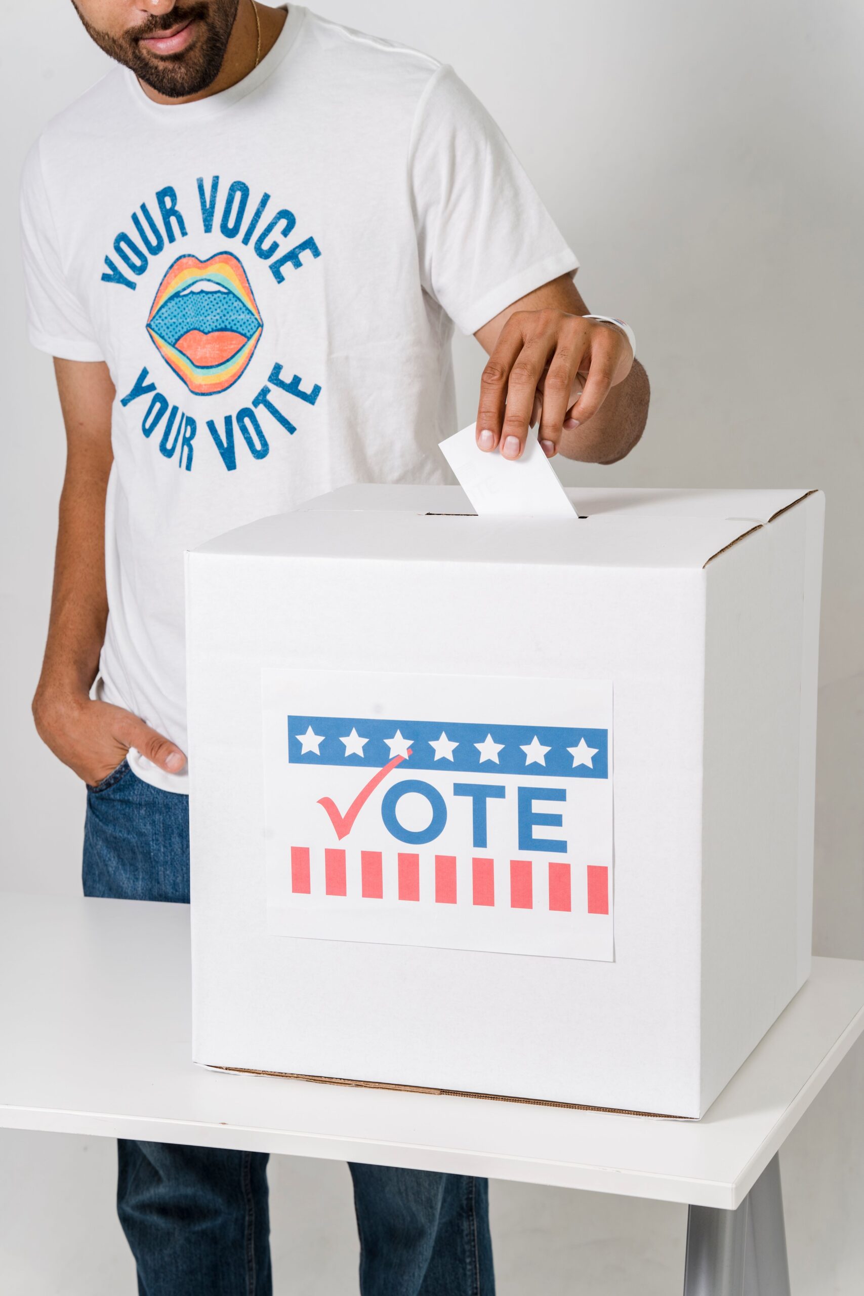 A voter places a ballot into a white box marked Vote