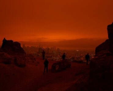 A city skyline under orange wildfire smoke haze