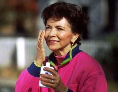 A woman applying sunscreen to her face outdoors