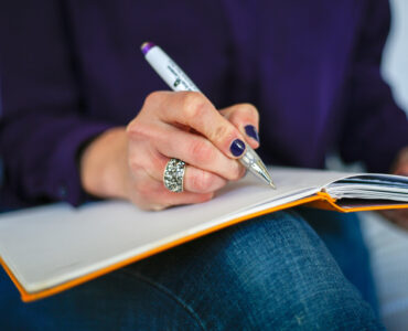 A person writing in a notebook with a pen