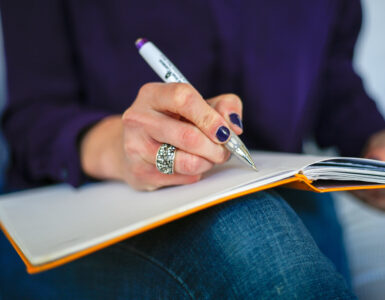 A person writing in a notebook with a pen