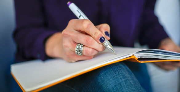 A person writing in a notebook while drafting a clear paragraph.