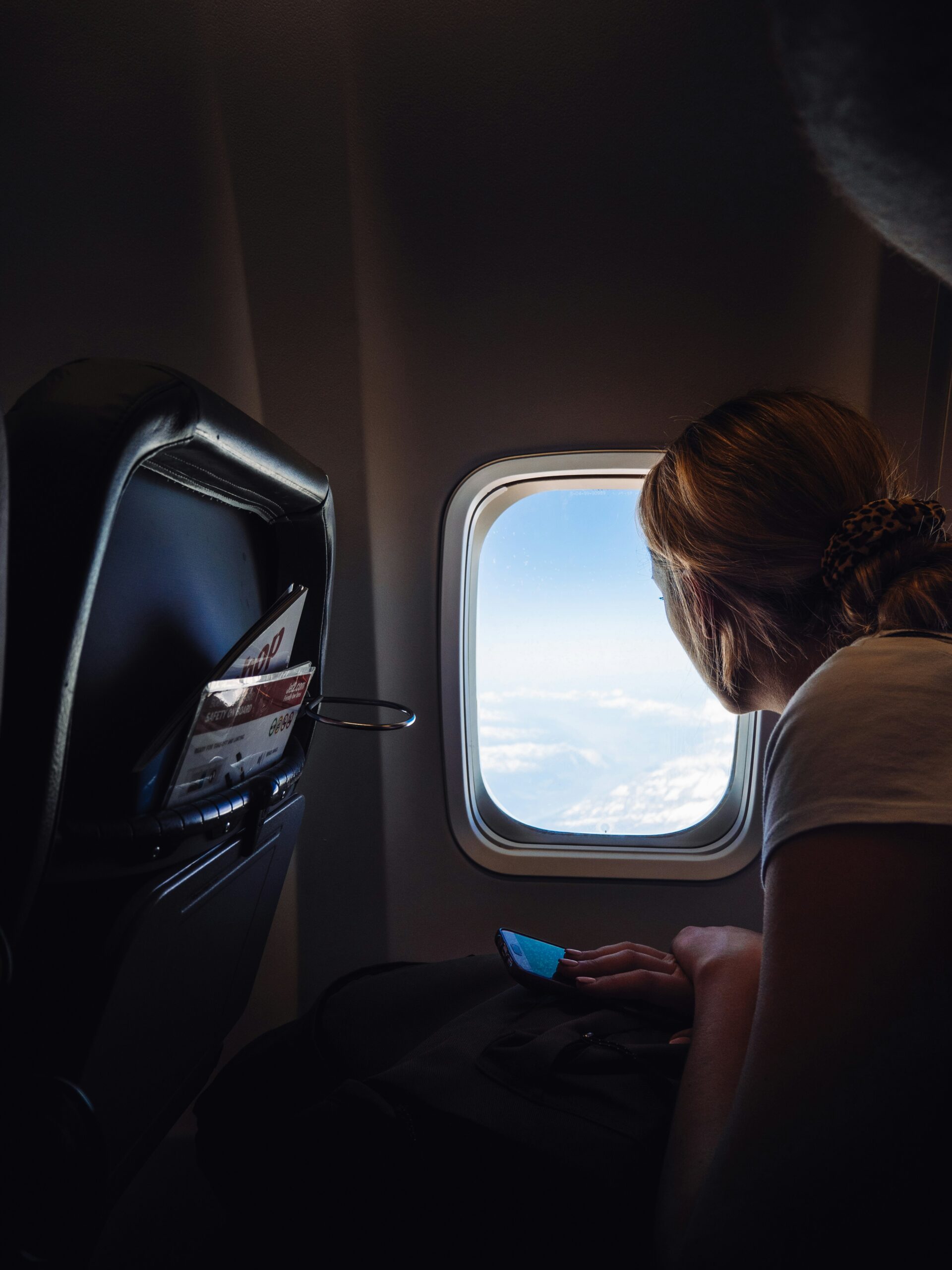 A passenger looks out an airplane window toward the horizon during flight