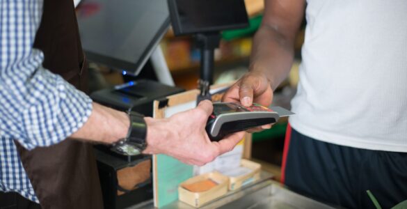 A payment card at a checkout terminal representing buy now, pay later and credit reporting decisions.