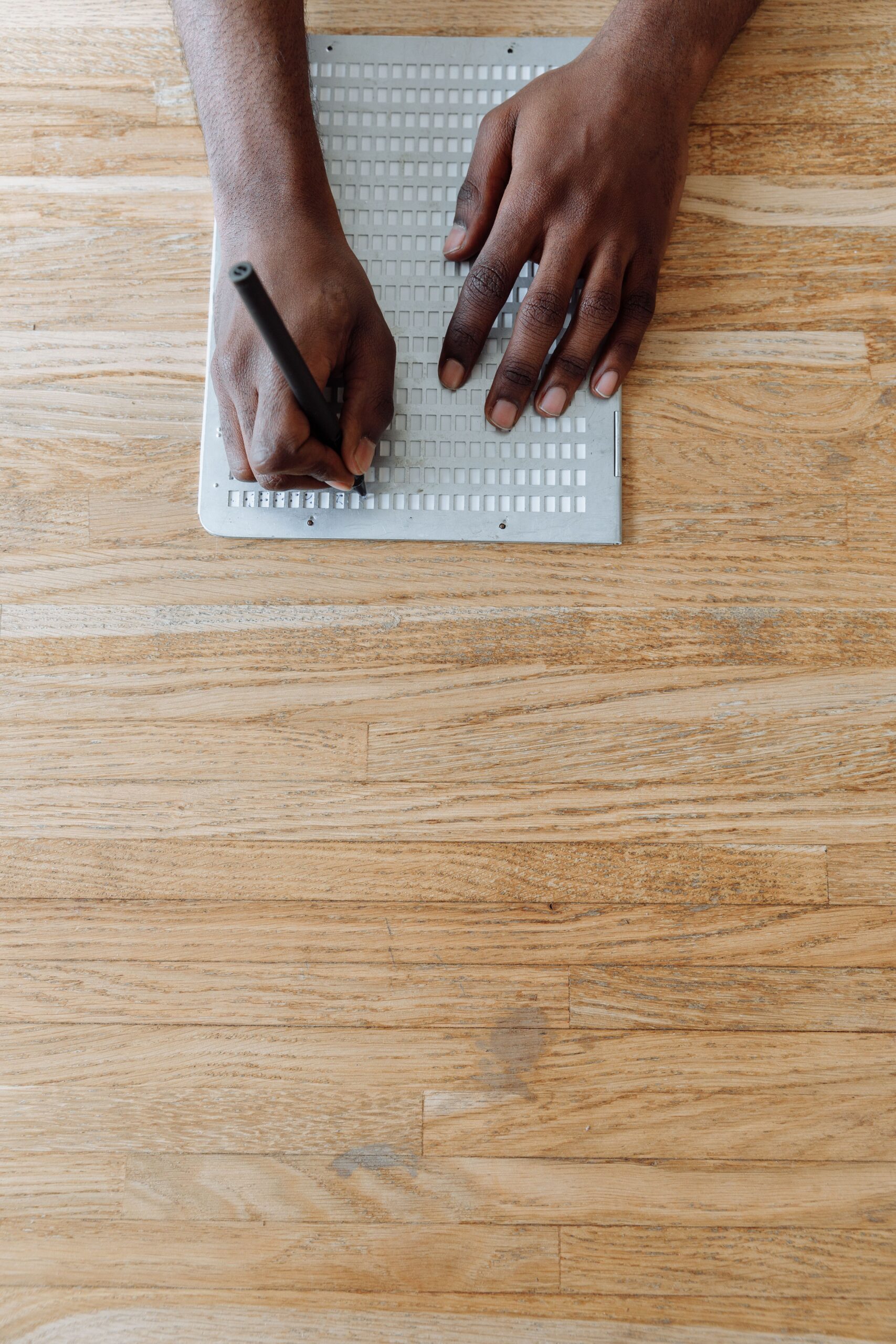 A person using a slate and stylus to write Braille on paper.